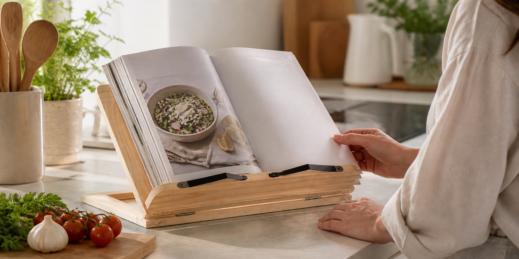 Wooden book easel holding an open cookbook on a kitchen countertop with a person reading while preparing food