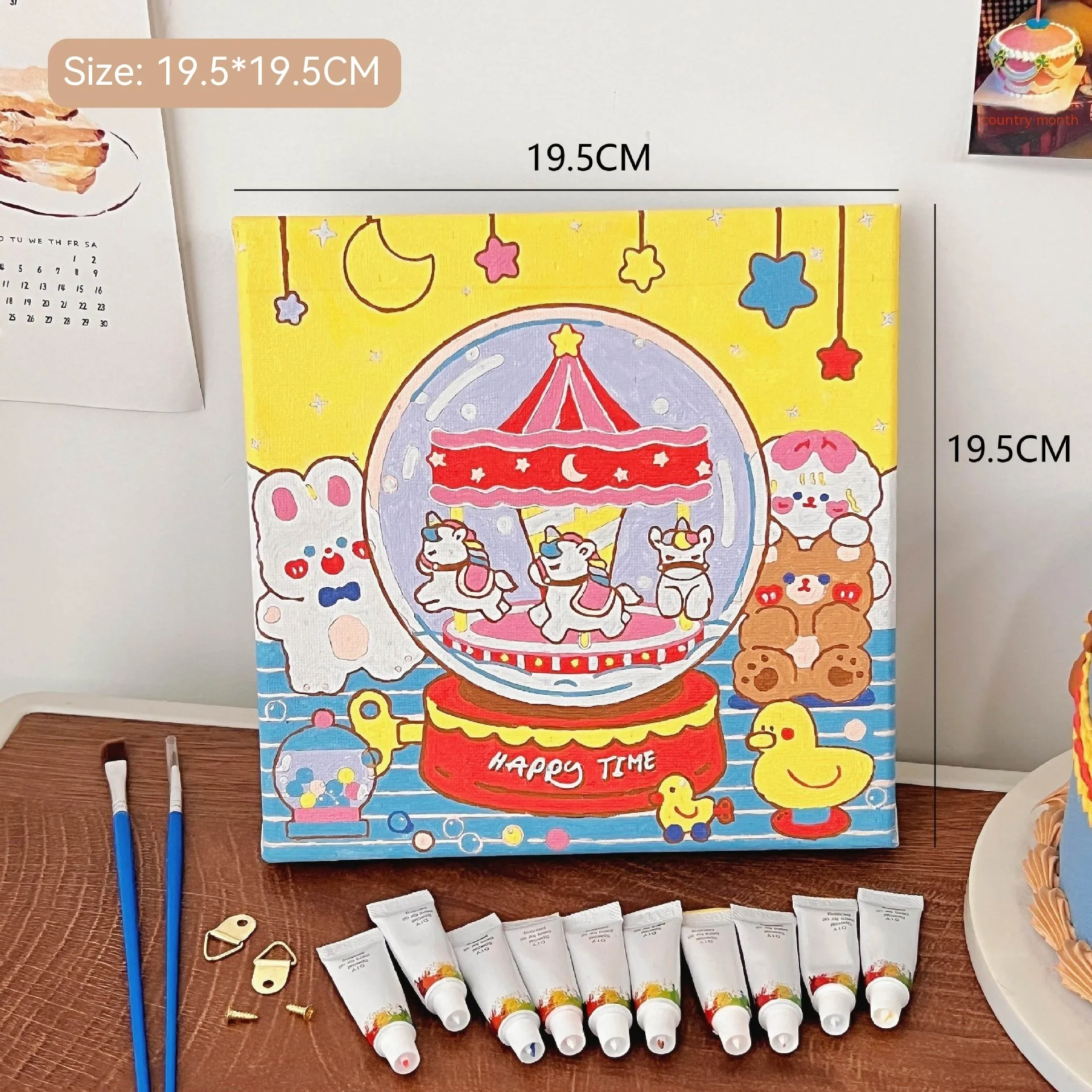 Mini DIY canvas painting kit with carousel inside a crystal ball design on a pre-printed canvas, including acrylic paint tubes and brushes arranged on a desk ready for painting