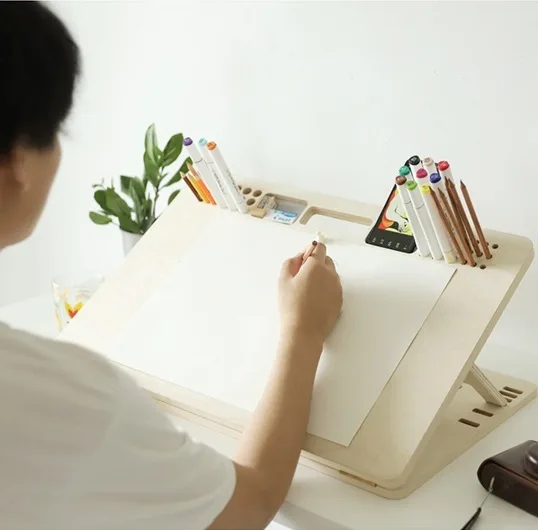 Adjustable drawing board tilted at illustration angle on desk