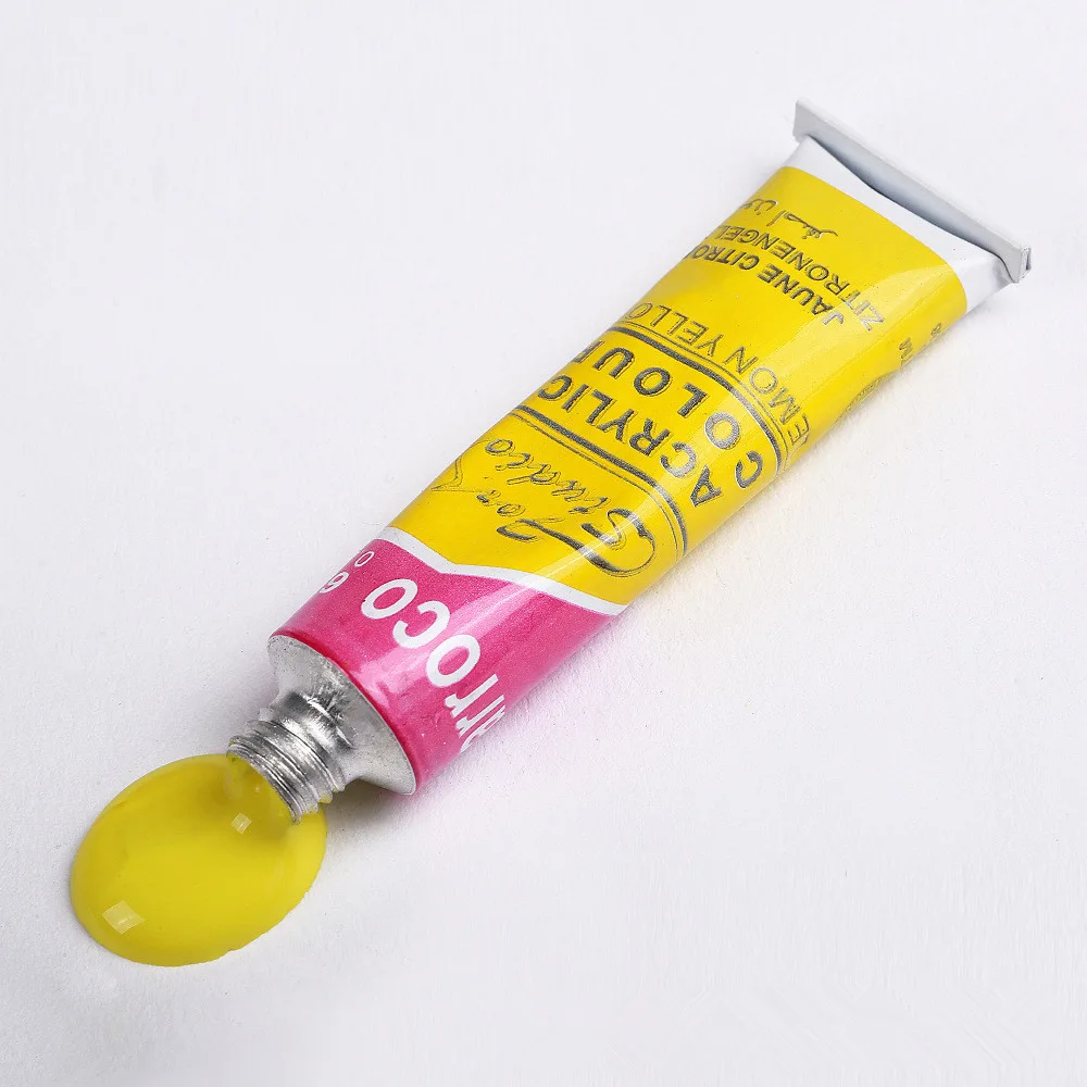Yellow acrylic paint tube from acrylic paint set with brush with paint squeezed onto surface