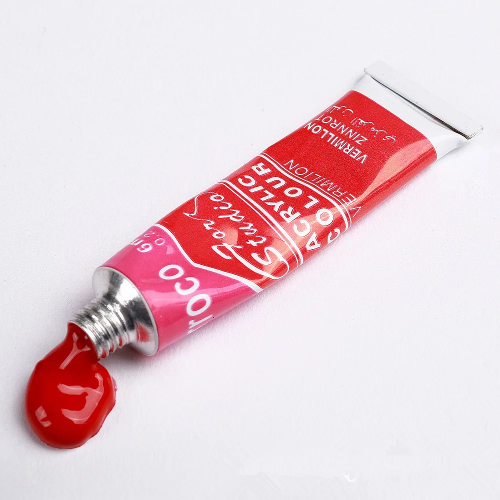 Red acrylic paint tube from acrylic paint set with brush with paint squeezed onto surface