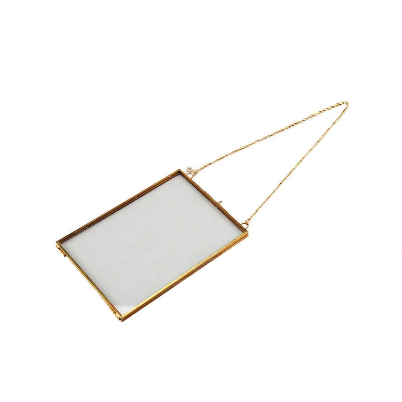 Vertical double-sided glass frame with brass edging on white wall