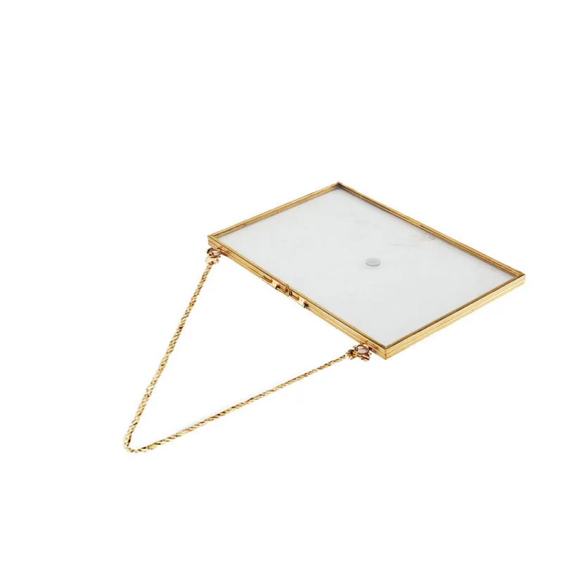 Horizontal double-sided glass frame with brass edging on white wall