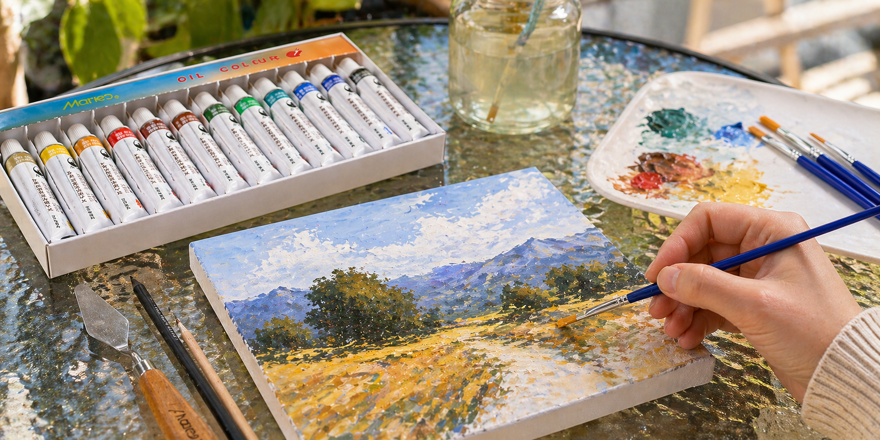 Beginner oil paint set in use on a glass table with artist painting a landscape canvas, palette with mixed colours, brushes, and paint tubes arranged naturally in a bright studio setting