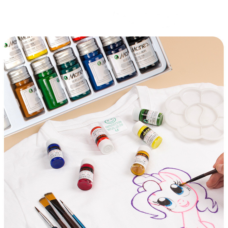 Close-up of fabric paint bottles with brushes and painted canvas