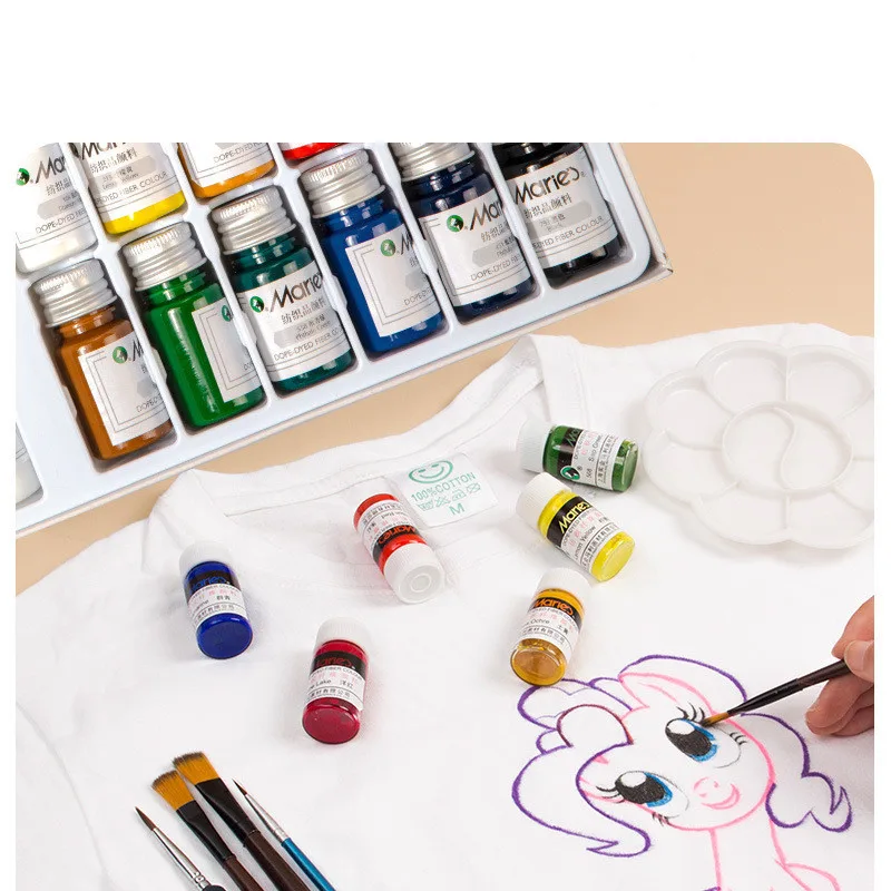 Close-up of fabric paint bottles with brushes and painted canvas