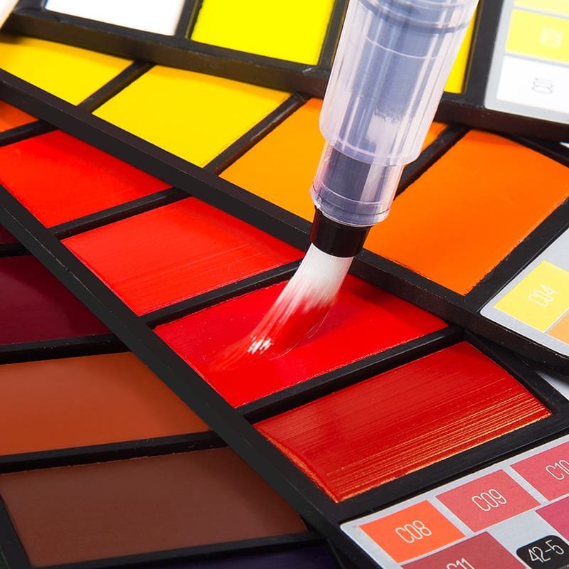 Close up of water brush pen on vibrant watercolour paint cakes